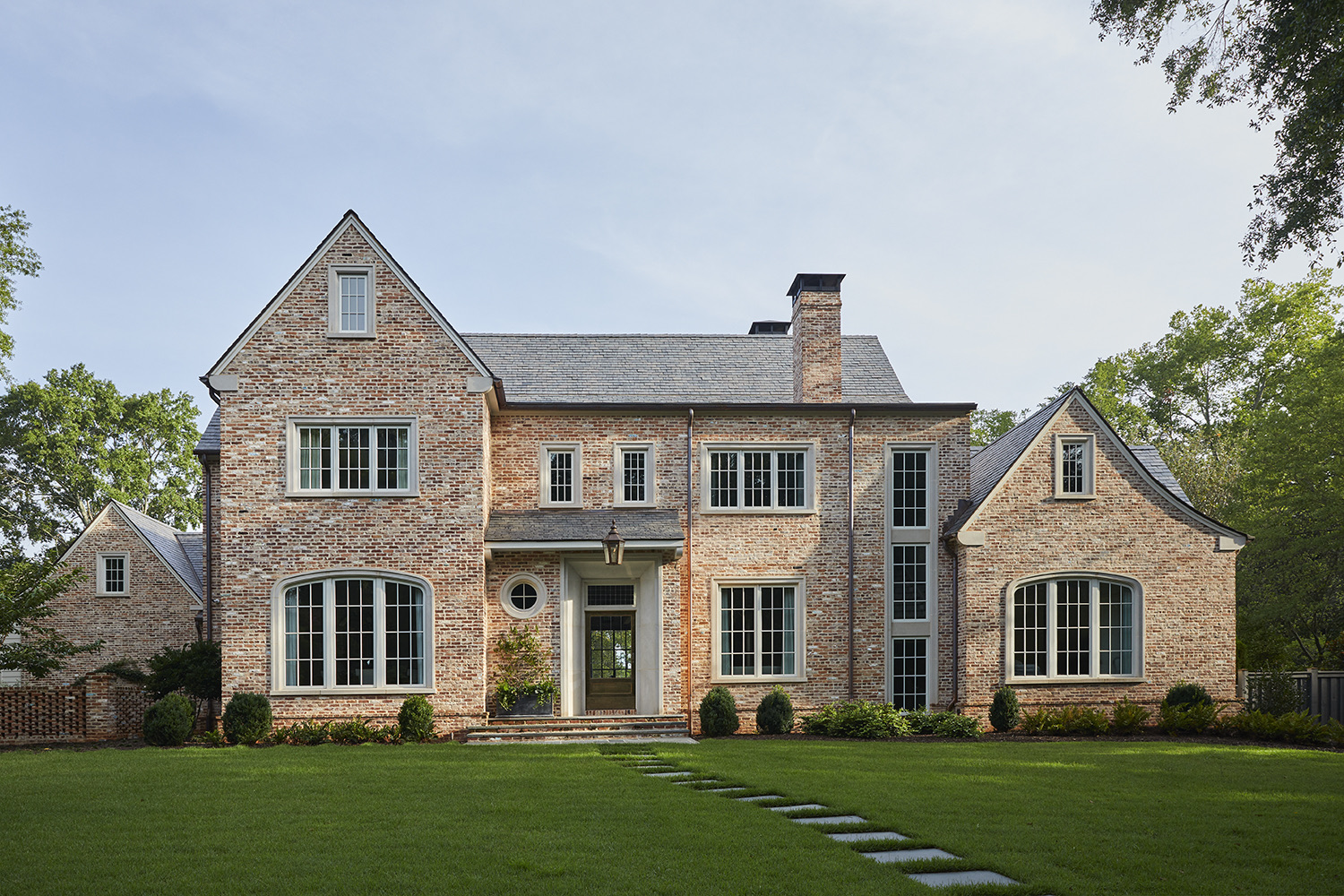 Brick Manor full front facade with gabled wings, slate roof, and stone walkway