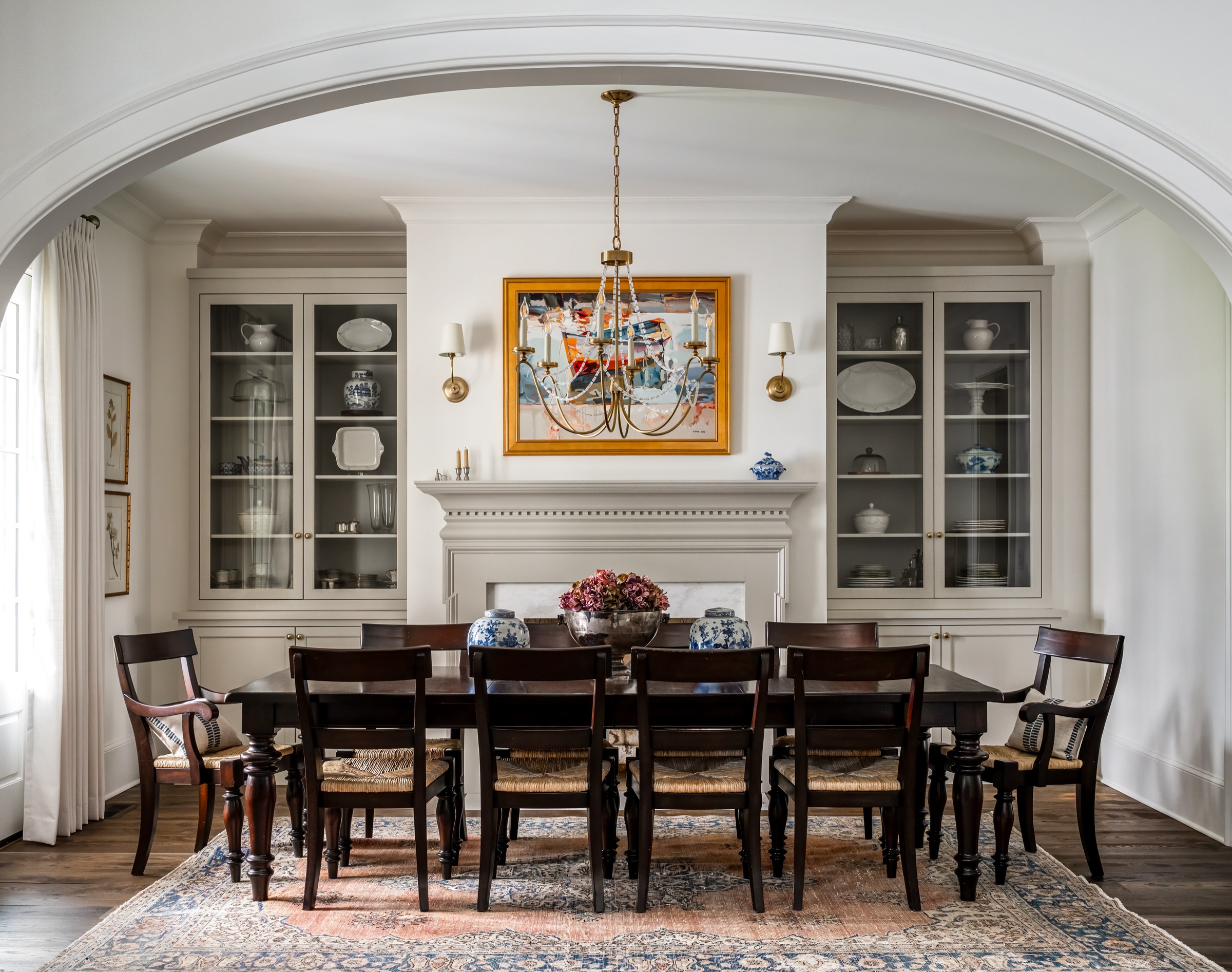 Formal dining room with paneled walls, antique sideboard, and brass chandelier